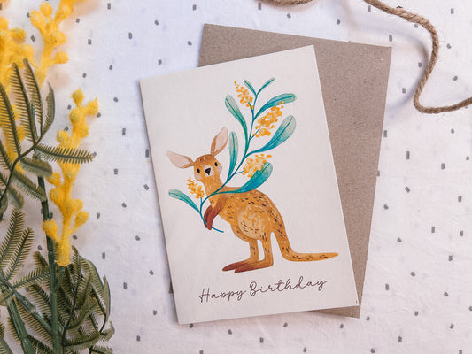 Illustrated kangaroo greeting card holding a wattle branch, hand-drawn Australian wildlife stationery